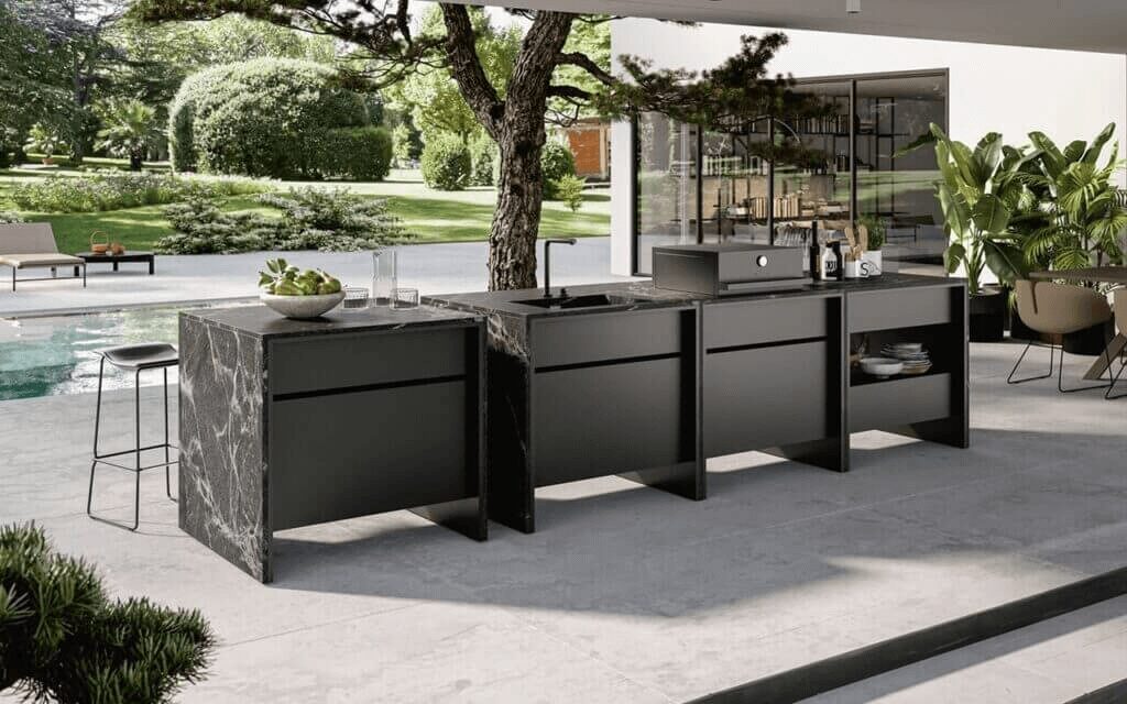 Modern Italian outdoor kitchen with sleek black stone countertops and stainless steel appliances, designed for outdoor dining and entertaining.