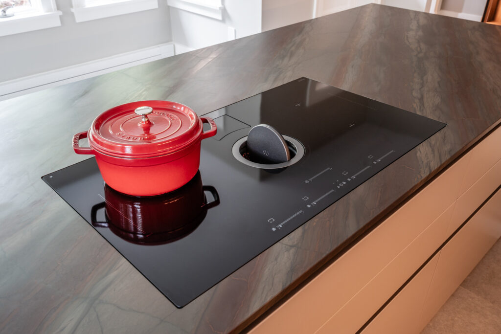 Hidden downdraft hood built into cooktop range on a kitchen island