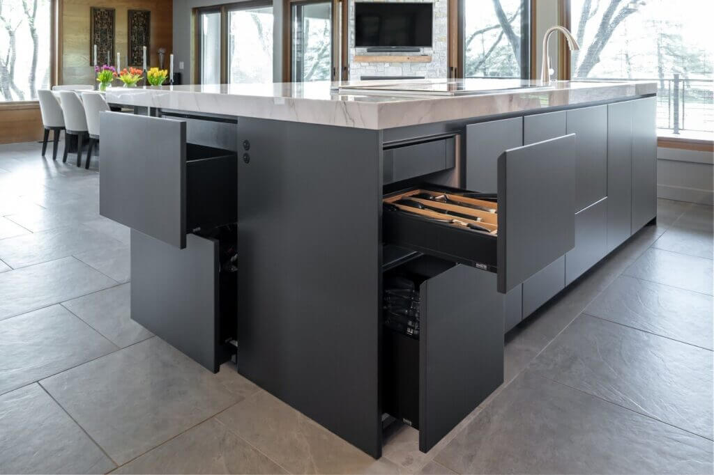 Modern minimalist kitchen design featuring sleek matte black cabinetry, integrated storage solutions, and a marble-topped island with built-in organization.